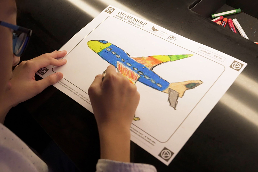 飛行機、チョウ、タカの輪郭が描かれた紙にお絵かきする。チームラボ《お絵かきフライト》©チームラボ ※参考画像